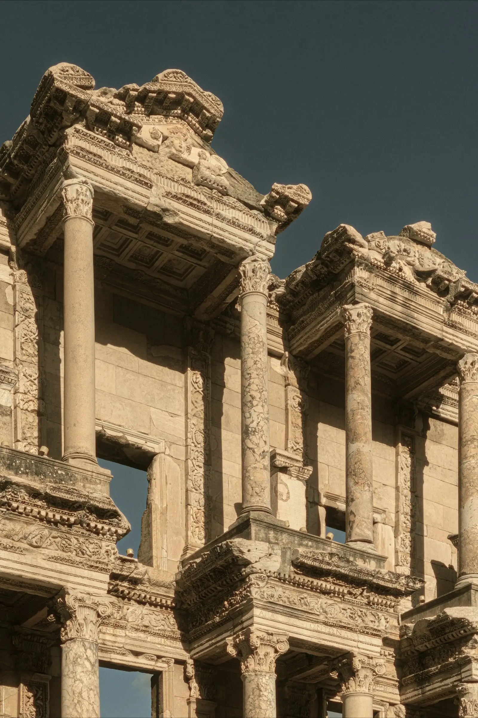 Upper columns and facade detail of the Library of Celsus against a clear sky